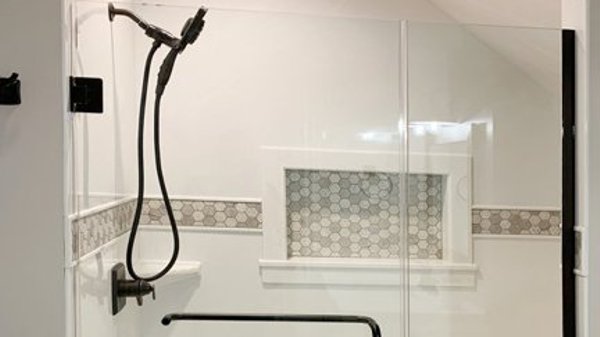 Finished shower with frameless glass doors and hexagon tile accent band