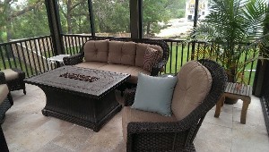 Screened porch furnished with wicker seating and a fire table